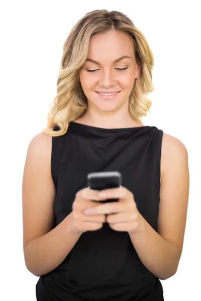 Cheerful gorgeous blonde in black dress texting Stock Picture