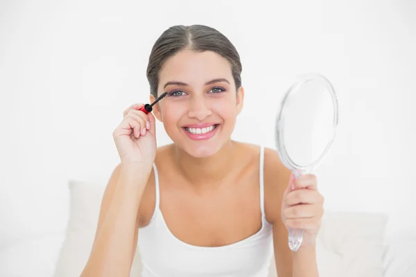 Model in white pajamas applying mascara Stock Photo