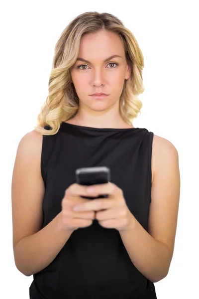 Serious gorgeous blonde in black dress texting Royalty Free Stock Photos