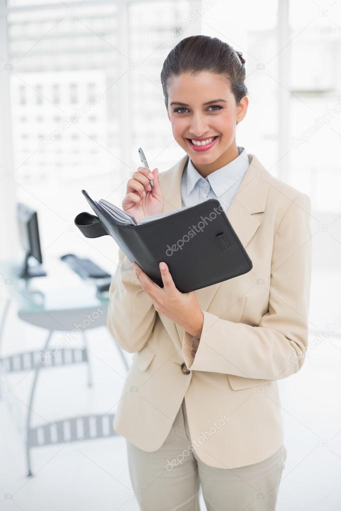 Pleased smart businesswoman filling an agenda