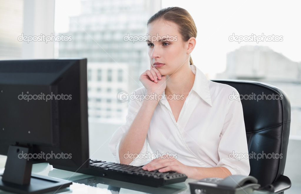 Thoughtful businesswoman sitting at desk looking at computer