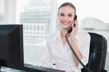 telefonda masa başında oturan gülümseyen iş kadını