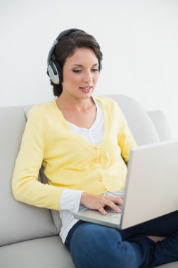 Sarı hırka bir dizüstü bilgisayar kullanırken müzik oldukça casual esmer