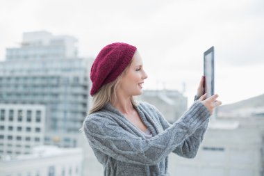 Tablet açık havada tutan güzel sarışın gülümseyerek