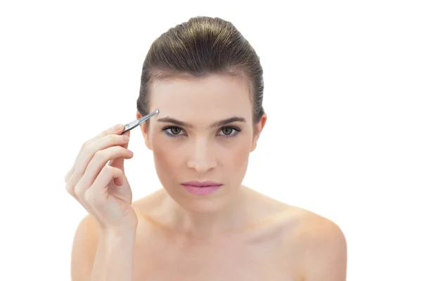 Serious model plucking her eyebrows — Stock Photo, Image