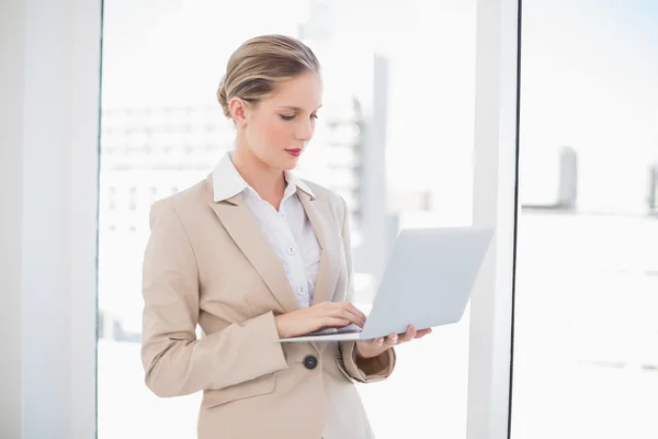 Serious blonde businesswoman using laptop — Stock Photo, Image