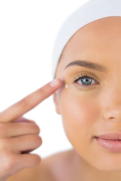 Attractive woman with headband on putting cream on her face — Stock Photo, Image