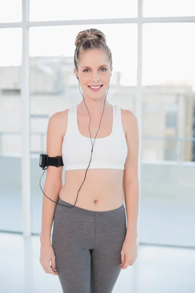 Smiling sporty blonde listening to music — Stock Photo, Image