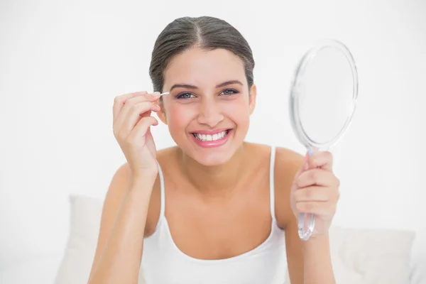 Model in white pajamas plucking her eyebrows — Stock Photo, Image