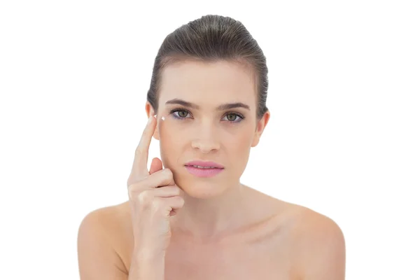 Modelo concentrado aplicando crema facial —  Fotos de Stock