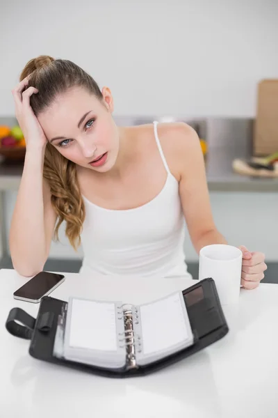 Stressad ung kvinna med en mugg med öppen dagbok — Stockfoto