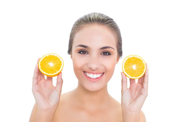 Улыбающаяся женщина держит две половинки апельсинов — стоковое фото