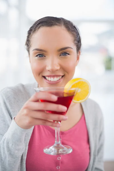 Smiling woman sitting on sofa and drinking cocktail — Stock Photo, Image