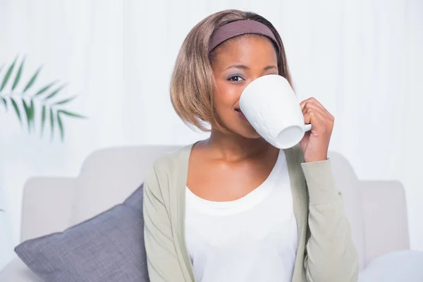 Atrakcyjna kobieta siedzi na kanapie, picia kawy — Zdjęcie stockowe