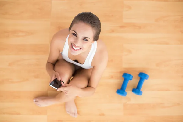 Lachende sportieve brunette houdt van een mobiele telefoon — Stockfoto