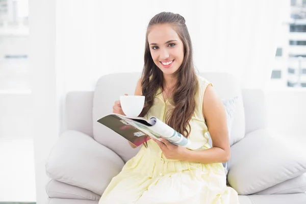 Smiling pretty brunette holding a magazine — Stock Photo, Image