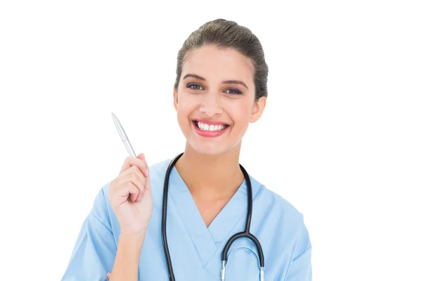 Pleased nurse in blue scrubs holding a pen — Stock Photo, Image