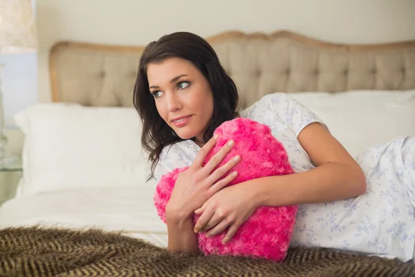 Calma mujer bonita abrazando una almohada en forma de corazón —  Fotos de Stock