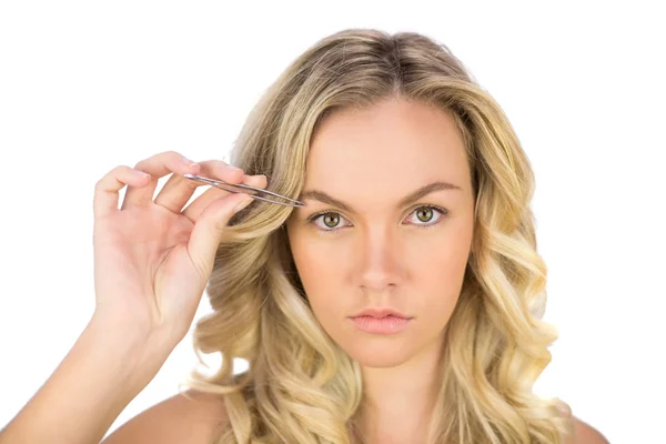 Serious curly haired blonde using tweezers — Stock Photo, Image