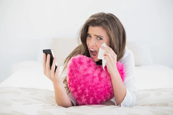 Depressieve vrouw in witte pyjama ophangen van haar mobiele telefoon — Stockfoto