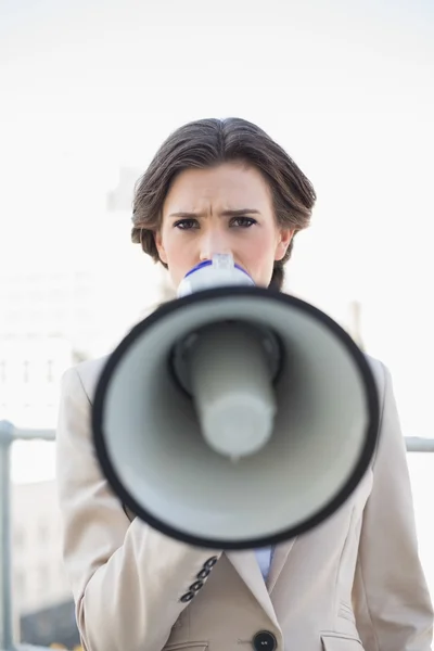 Frowning stylish businesswoman speaking in a megaphone — Stock Photo, Image