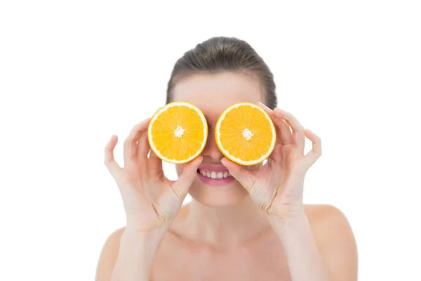 Juguetona modelo ocultando sus ojos detrás de mitades naranjas — Foto de Stock