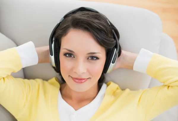 Glimlachend casual brunette in gele vest genieten van muziek — Stockfoto