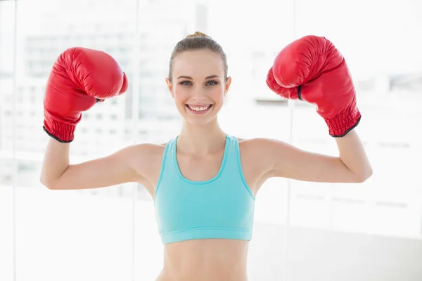 Sporty smiling woman holding up boxing gloves — Stock Photo, Image