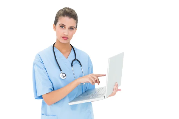 Stern nurse in blue scrubs using a laptop — Stock Photo, Image