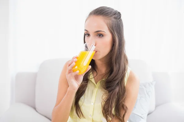 Morena bonita bebendo um copo de suco de laranja — Fotografia de Stock