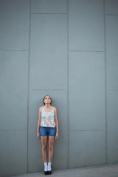 Belle femme debout devant un mur gris — Photo