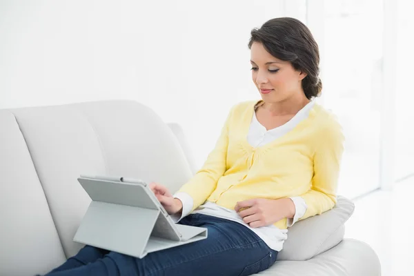 Conteúdo casual morena em casaco amarelo usando um tablet pc — Fotografia de Stock