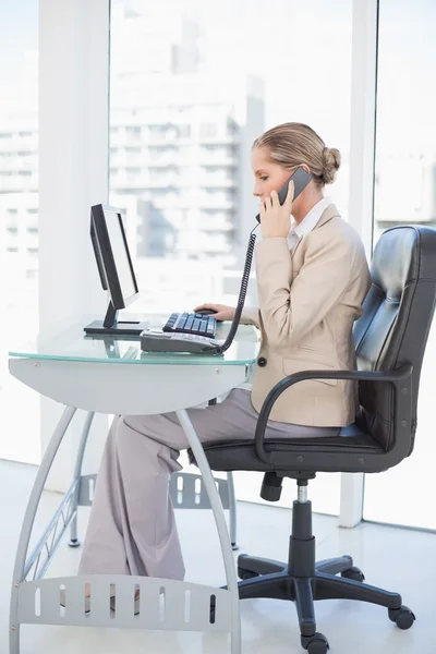 Blonde zakenvrouw gericht op de telefoon — Stockfoto