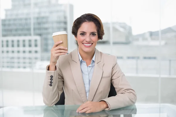 Smiling businesswoman holding disposable cup at her desk — Stock Photo, Image