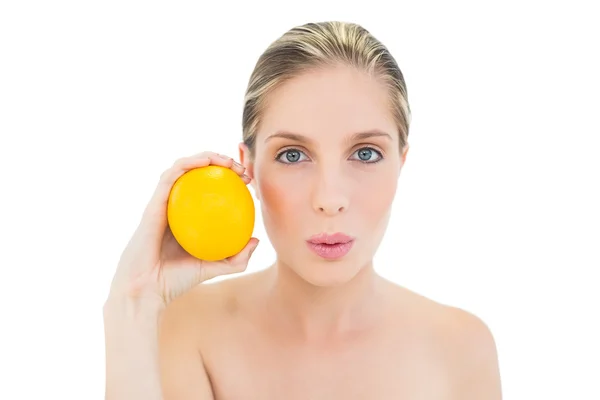 Mulher loira fresca atraente bebendo e segurando uma laranja — Fotografia de Stock