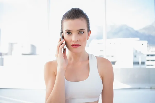 Unsmiling fit model in sportswear making a phone call — Stock Photo, Image