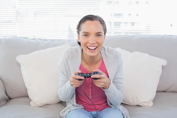 Lächelnde Frau sitzt auf Sofa und spielt Videospiele — Stockfoto