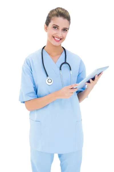 Enfermeira alegre em esfoliação azul usando um tablet pc — Fotografia de Stock
