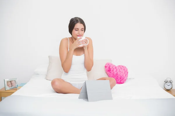 Peaceful young model in white pajamas enjoying coffee smell — Stock Photo, Image