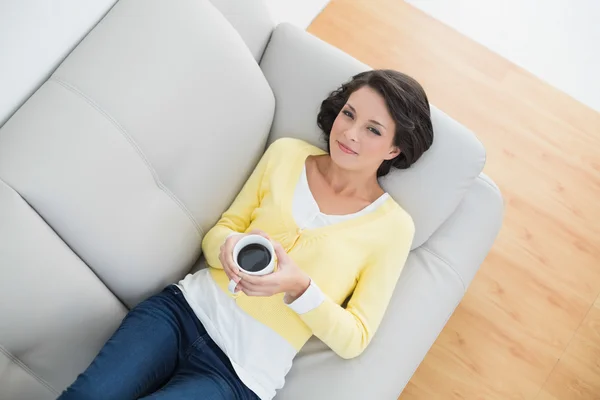 Calm casual brunette in yellow cardigan holding a mug of coffee — Stock Photo, Image