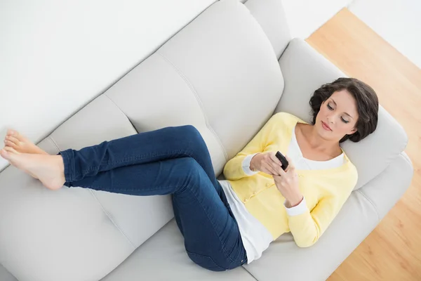 Brune décontractée détendue en cardigan jaune textos avec un téléphone portable — Photo