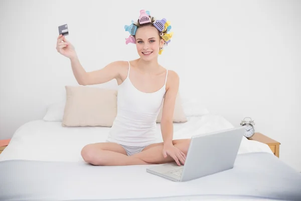 Relaxed woman in hair curlers shopping online with a laptop — Stock Photo, Image