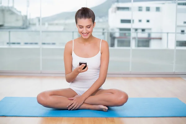 Kvinnan i vit sportkläder med hennes mobiltelefon — Stockfoto