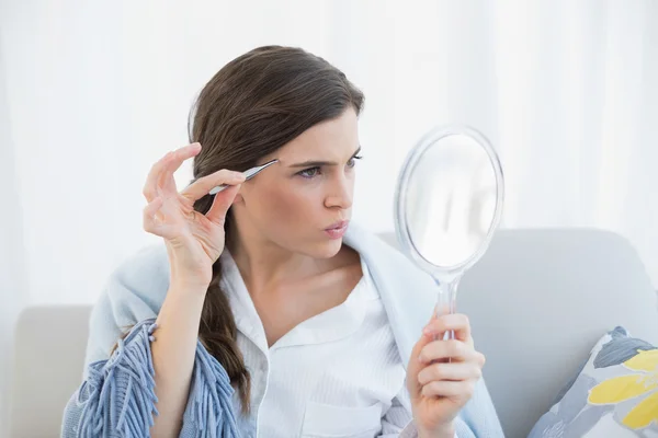 Mujer enfocada en pijamas blancos arrancándose las cejas — Foto de Stock