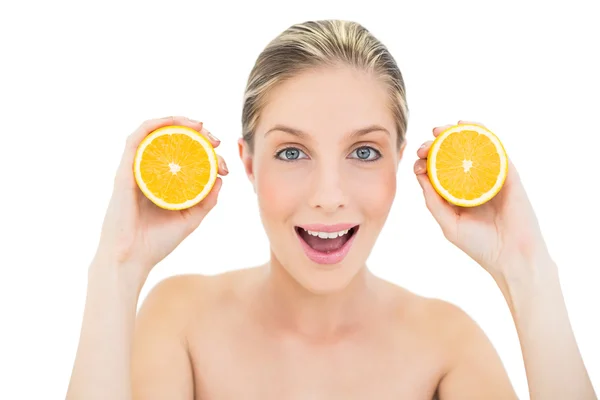 Mulher loira fresca divertida segurando duas laranjas metades — Fotografia de Stock