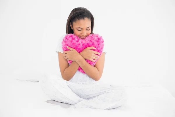 Мирная молодая модель обнимает подушку в форме сердца — стоковое фото