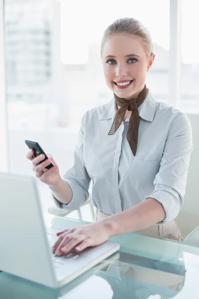 Donna d'affari dai contenuti biondi che utilizza laptop e smartphone — Foto Stock