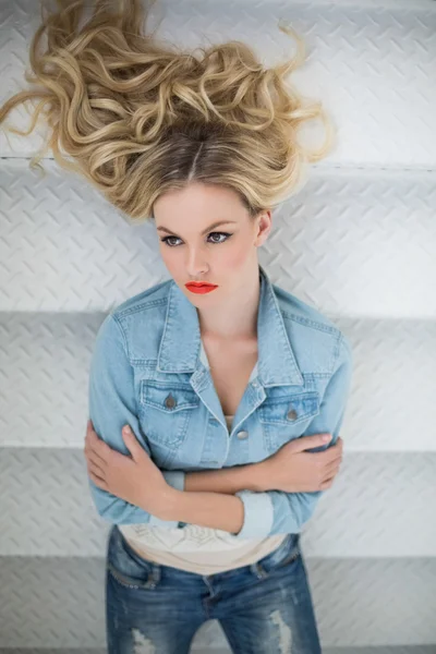 Thinking blonde wearing denim clothes lying on stairs — Stock Photo, Image