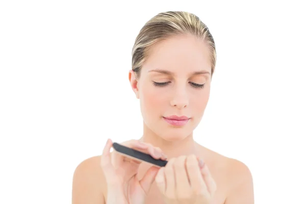 Serious fresh blonde woman filing her nails — Stock Photo, Image