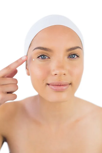 Attraente donna weaing fascia mettendo crema sul suo viso — Foto Stock
